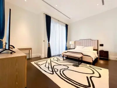 Luxurious bedroom with elegant decor and large window, featuring a stylish rug and modern furniture.