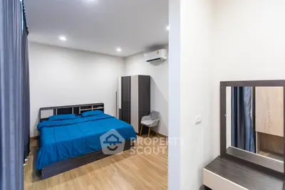 Modern bedroom with wooden flooring and stylish furniture, featuring a cozy bed and a sleek wardrobe.