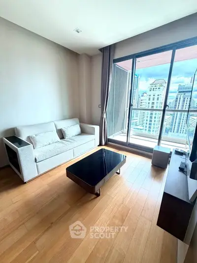 Modern living room with city view, featuring sleek furniture and large windows for natural light.