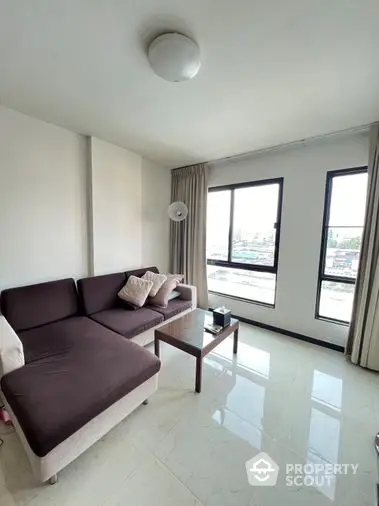 Bright and airy living space with glossy tiled flooring, comfortable sofa, and large windows offering an urban view, perfect for modern living.