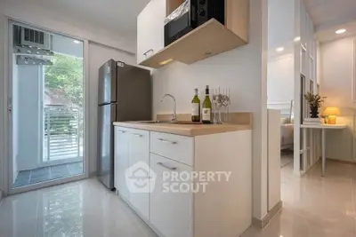 Modern kitchen with sleek design, featuring stainless steel fridge and open layout leading to a bright balcony.