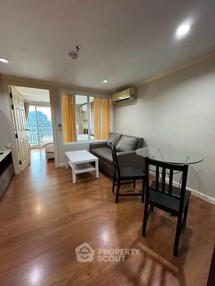 Spacious living room with modern furniture and wooden flooring in a high-rise apartment.