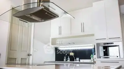 Modern kitchen with sleek cabinetry and built-in oven, featuring a stylish range hood and ample counter space.