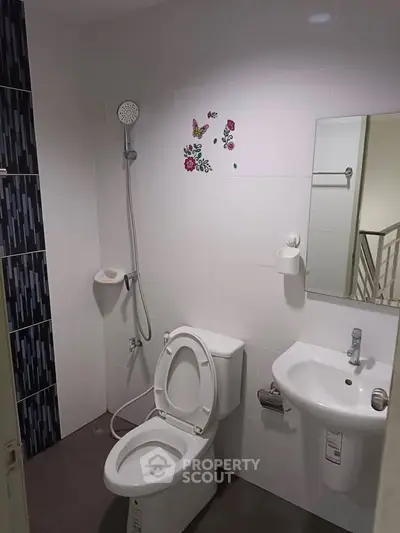 Modern bathroom with shower and floral wall decor in real estate property.