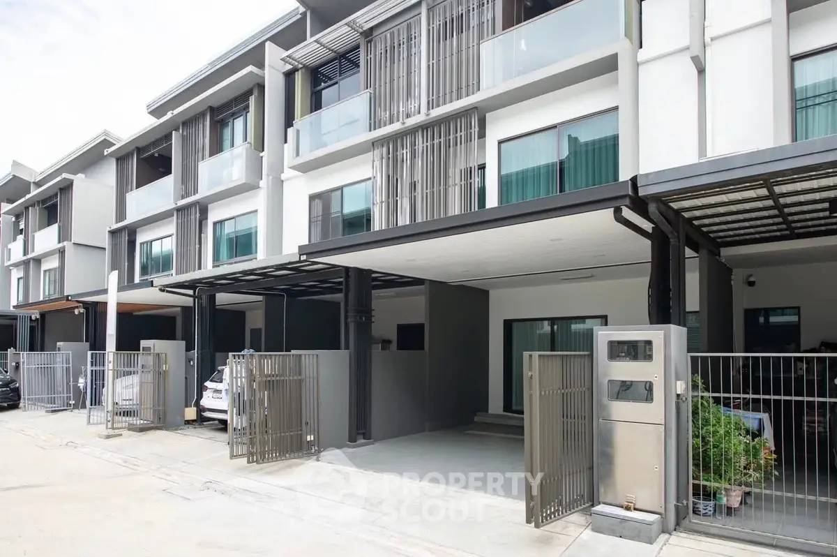 Modern townhouse exterior with sleek design and gated parking area.