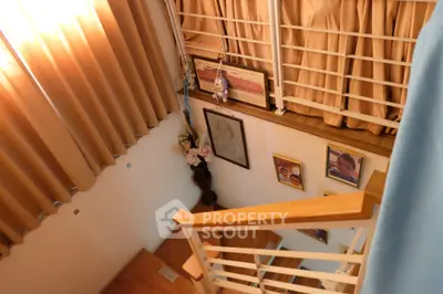 Charming staircase with wooden railing and decorative wall art, bathed in warm natural light from large windows.