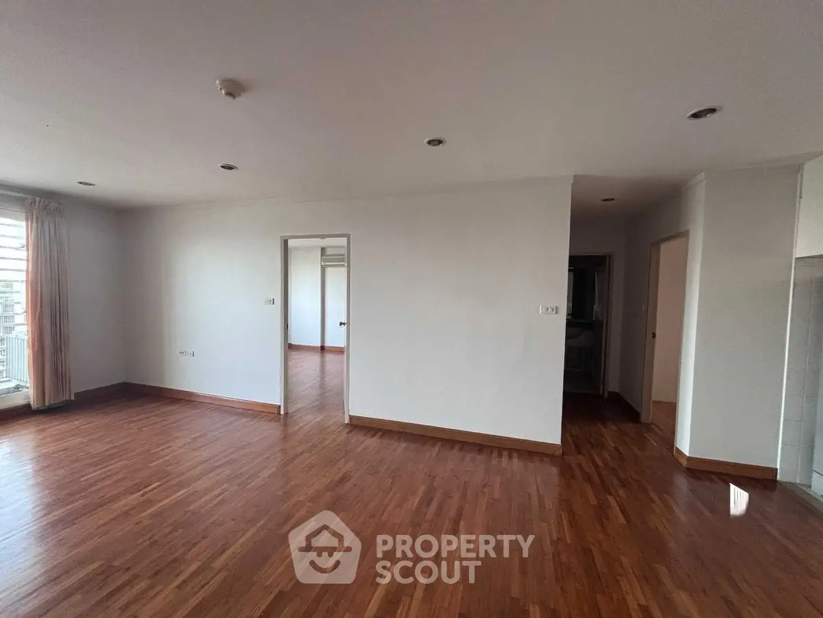 Spacious empty living room with wooden flooring and natural light
