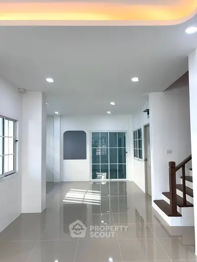 Spacious modern living room with glossy tiled floors and elegant staircase