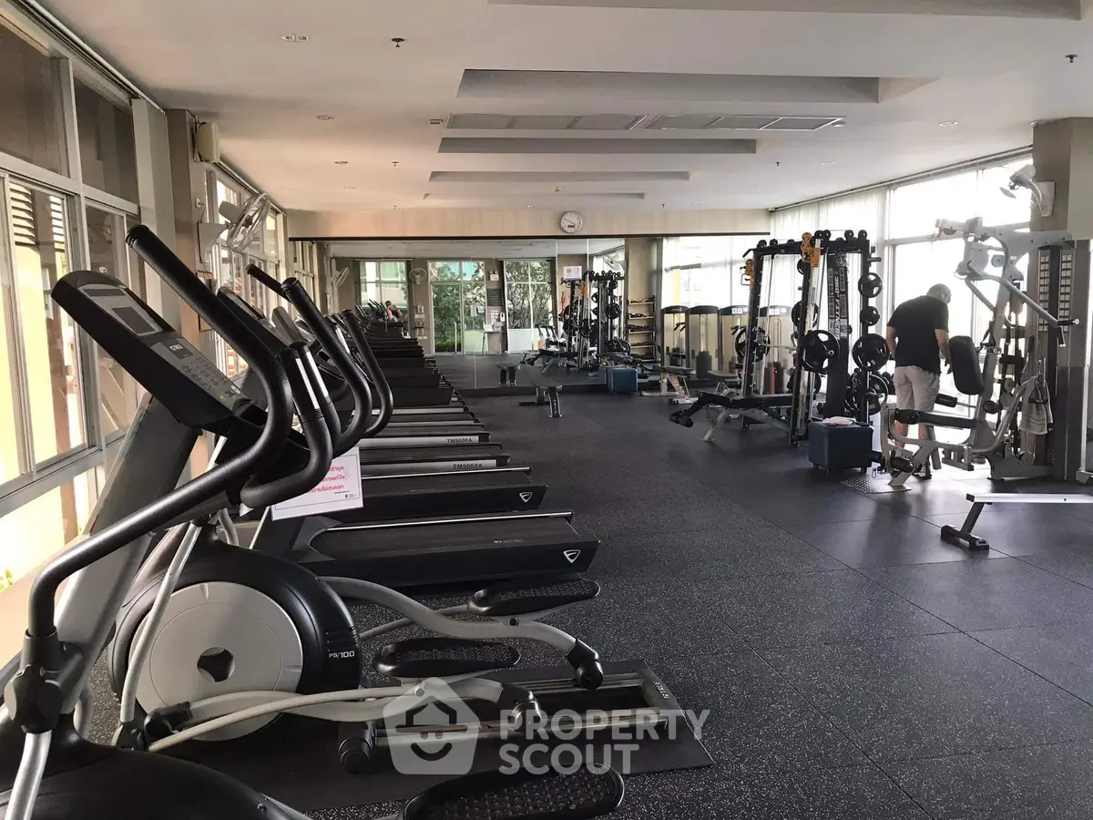 Spacious modern gym with state-of-the-art fitness equipment and natural lighting.