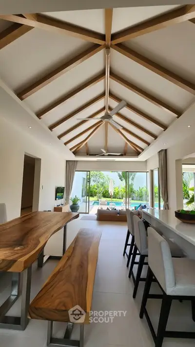 Stunning open-plan living space with vaulted ceiling and pool view, perfect for luxury living.
