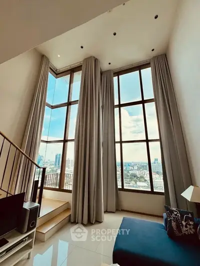 Stunning high-ceiling living room with floor-to-ceiling windows and city view.