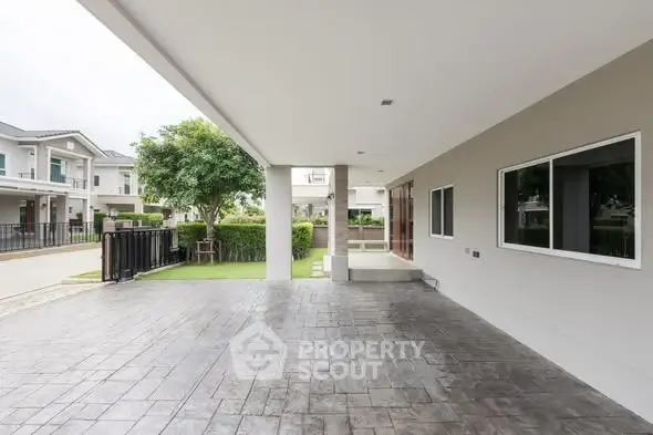 Spacious modern house exterior with covered driveway and lush greenery.