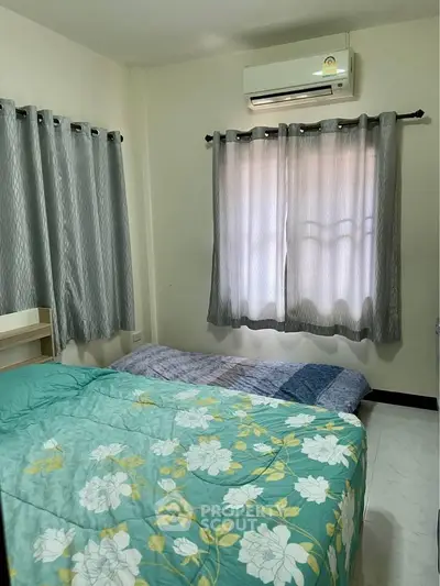 Cozy bedroom with floral bedding and air conditioning, perfect for a restful retreat.
