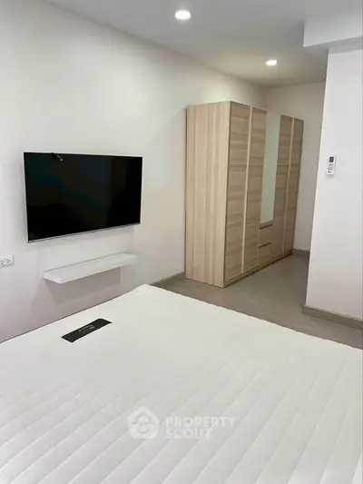 Modern bedroom with sleek TV and spacious wardrobe in a stylish apartment.