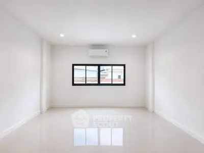 Spacious empty room with large window and air conditioning, perfect for customization.
