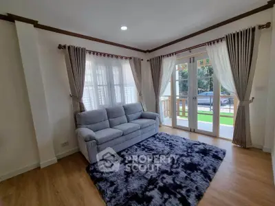 Charming living room with cozy sofa and elegant curtains, featuring a plush rug and natural light from large windows.
