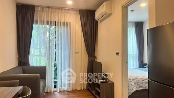 Cozy living room with modern furniture and natural light, adjacent to a stylish bedroom.