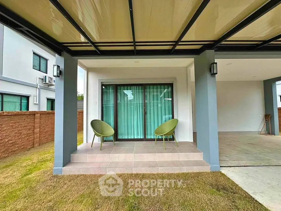 Modern house exterior with covered patio and green chairs, showcasing contemporary design and spacious outdoor area.