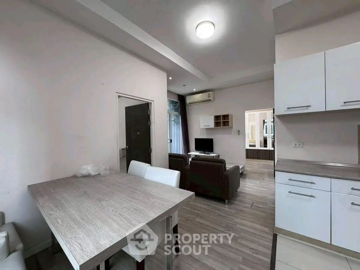 Modern open-plan living room with dining area and sleek kitchen cabinetry.