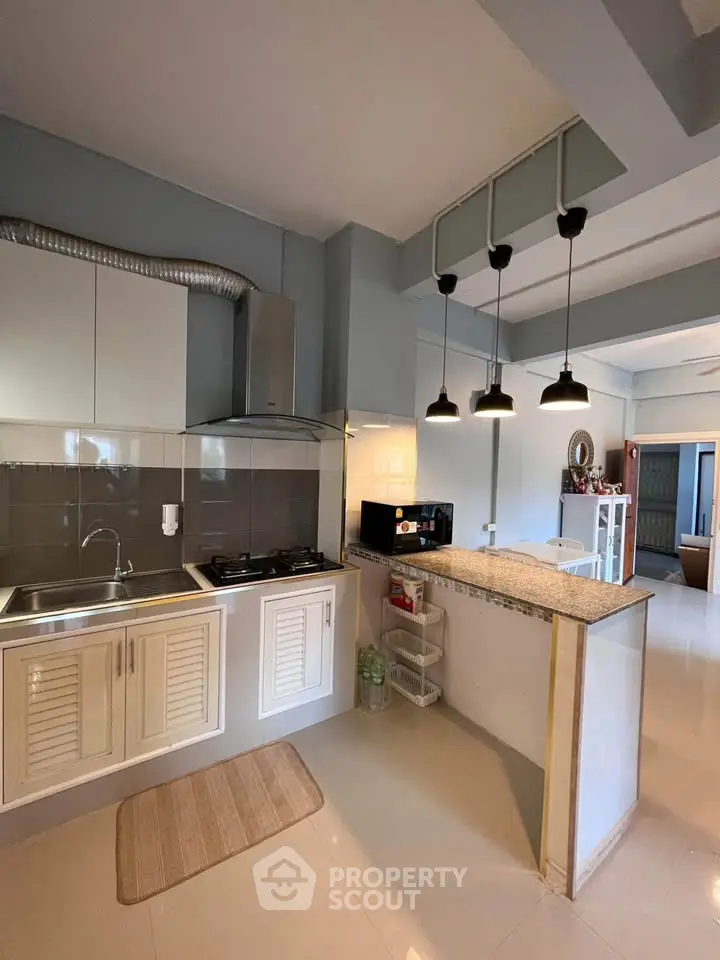 Modern kitchen with sleek design, featuring gas stove and stylish lighting, perfect for culinary enthusiasts.