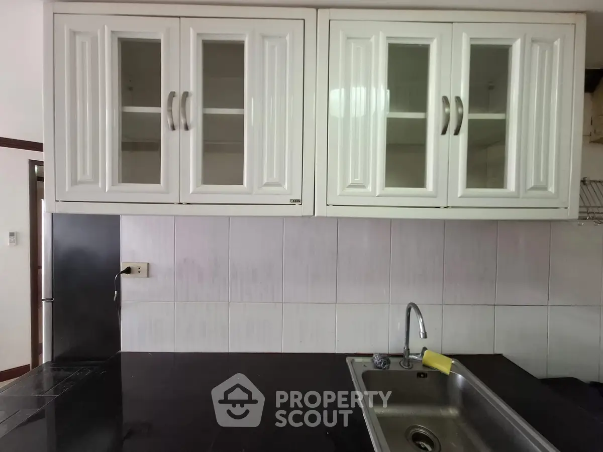 Modern kitchen with sleek black countertop and white cabinets, featuring a stainless steel sink and elegant design.