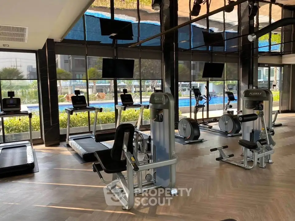 Modern gym with state-of-the-art equipment and pool view in luxury real estate property.