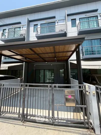 Modern townhouse exterior with gated parking and sleek design.