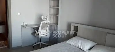 Modern bedroom with study area featuring sleek desk and ergonomic chair.