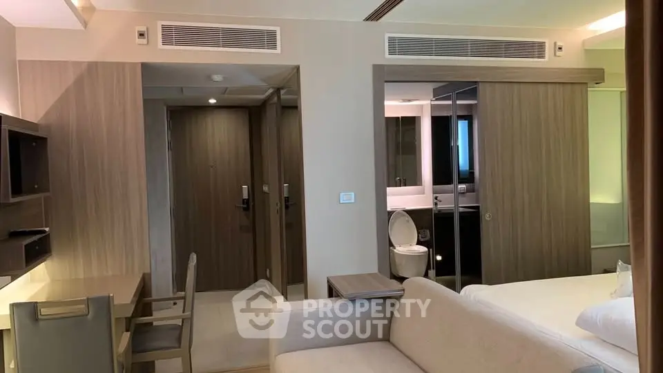 Modern hotel room with sleek design, featuring a cozy bed, stylish desk, and elegant bathroom.