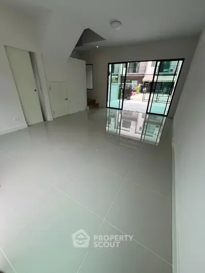 Spacious modern living room with large windows and glossy tiled floors