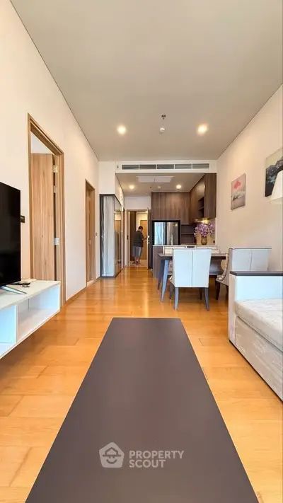Modern open-plan living room with wooden flooring and stylish kitchen area