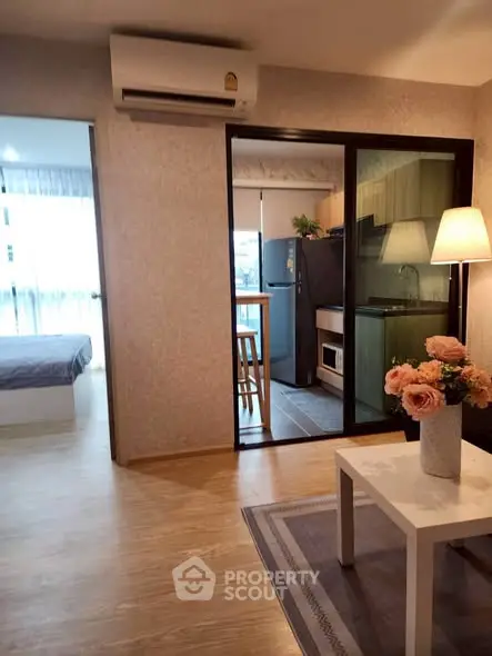 Modern apartment interior with open living room, kitchen, and bedroom view, featuring stylish decor and wooden flooring.