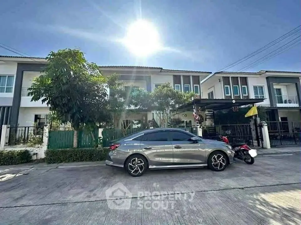 Modern townhouse exterior with parked car under bright sun