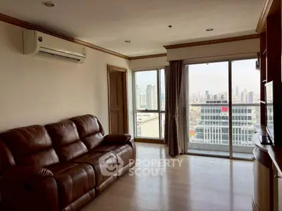 Spacious living room with leather sofa and city view from large windows.