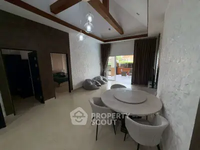 Spacious living room with modern dining area and large windows opening to a balcony.