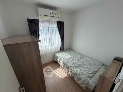 Cozy bedroom with natural light and air conditioning, perfect for relaxation.