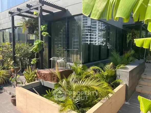 Modern building exterior with lush greenery and large windows, showcasing urban garden design.