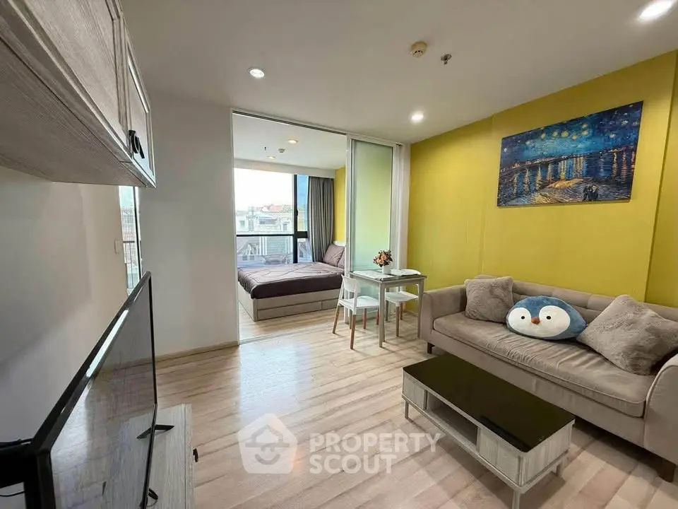Modern living room with cozy decor and open view to bedroom, featuring stylish furniture and bright ambiance.