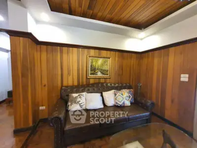 Cozy living room with wooden paneling and stylish leather sofa