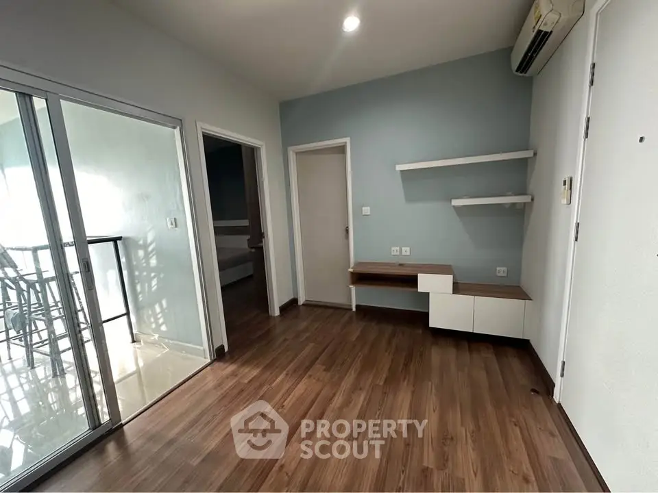 Modern living room with wooden flooring and balcony access in stylish apartment.