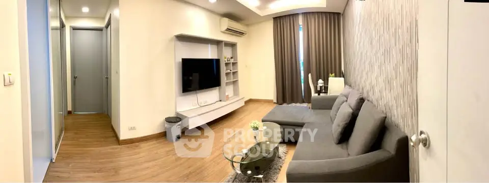Modern living room with sleek furniture and stylish decor, featuring a large TV and cozy seating area.