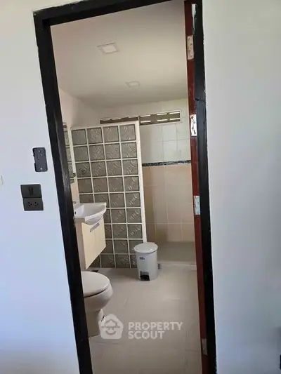 Modern bathroom with glass block shower and sleek fixtures in a contemporary home.