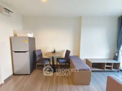 Modern living room with sleek furniture and natural light, featuring a compact dining area and stylish decor.