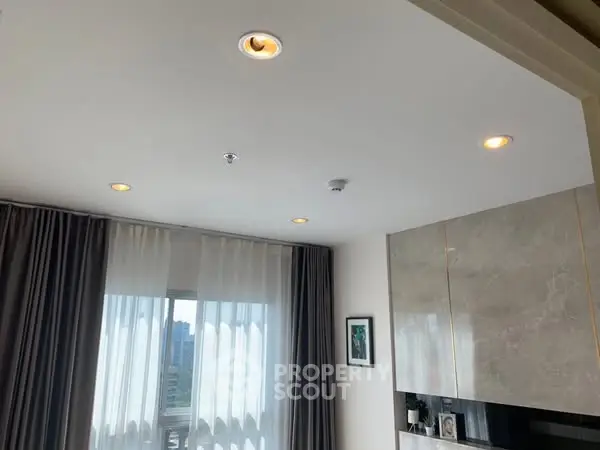 Modern living room with large window and elegant ceiling lights