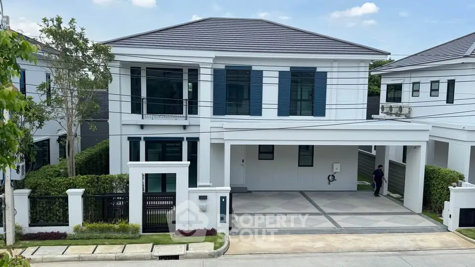 Elegant modern two-story house with spacious driveway and lush greenery.