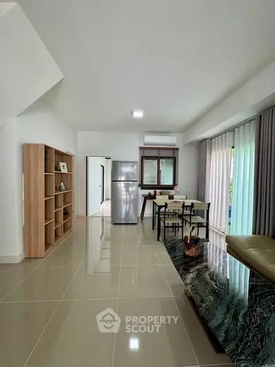 Modern open-plan living room with dining area and sleek kitchen appliances.