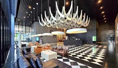Luxurious modern lobby with elegant seating and striking chandelier in upscale building.