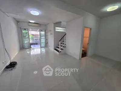 Spacious modern living room with glossy tile flooring and staircase in a bright open layout.