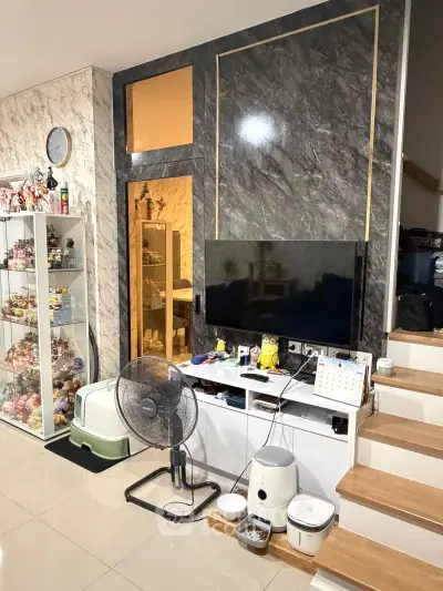Modern living room with marble accent wall, TV, and display shelves in stylish home interior.