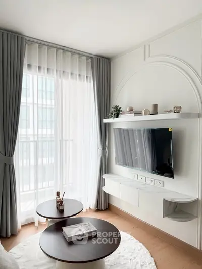 Modern living room with stylish decor and natural light, featuring a wall-mounted TV and elegant curtains.